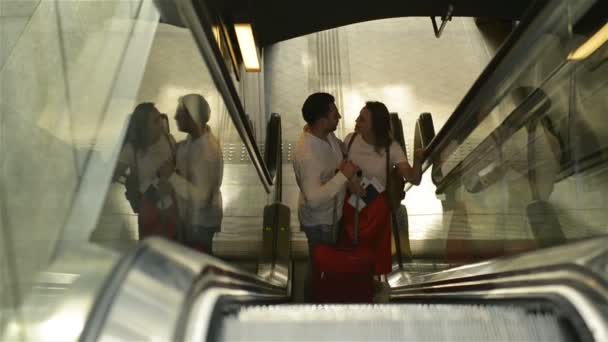 Pareja amorosa en la escalera mecánica en el aeropuerto. Un chico y su novia viajan juntos. Las personas con aspecto caucásico tienen buena luna de miel . — Vídeo de stock