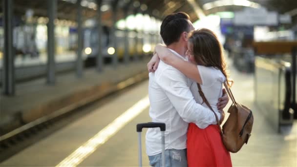 Triste jovem apaixonado acariciando e dizendo adeus a sua namorada na estação ferroviária antes de partir no dia ensolarado . — Vídeo de Stock