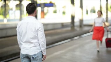 Tren istasyonunda çift yavaş hareket görünümü. Yakışıklı Erkek Arkadaşı Uzun Bir Yolculuktan Sonra Kız Arkadaşıyla Buluşuyor.
