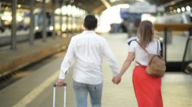 Tren istasyonunda bavulu olan bir çift koşuşturuyor. Elinde Pasaport Tutan Kadın.