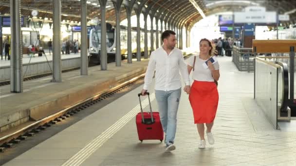 Felice sorridente giovane coppia in esecuzione sulla piattaforma stazione ferroviaria. Stanno parlando tra loro. . — Video Stock