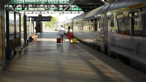 Casal a correr com uma mala numa estação de comboios. Mulher segurando passaportes em suas mãos enquanto o trem está ausente . — Vídeo de Stock