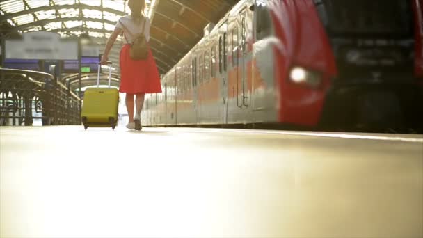 Unga kaukasiska kvinna med resväska kör för att fånga tåget i innan det lämnar stationen utan henne. — Stockvideo