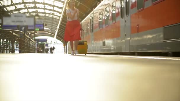 Unga kaukasiska kvinna med resväska kör för att fånga tåget i innan det lämnar stationen utan henne. — Stockvideo