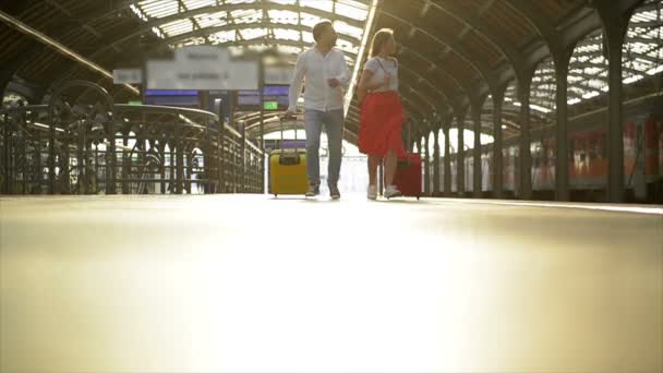 Running paar met een koffer in een trein station. Vrouw die paspoorten in haar handen houdt terwijl de trein vertrekt. — Stockvideo