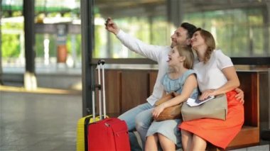 Tatil Zamanı Kayalar. Gülümseyen Güzel Aile Havaalanında Uçuş beklerken Akıllı Telefon ile Selfie Taking veya Tren İstasyonu'nda Tren.