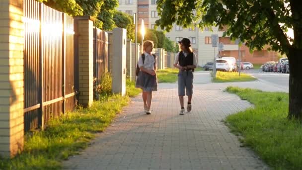 Két iskolás megy iskolába hátizsákok. Aranyos gyerekek Teen Girl és fiú táskák vissza az iskolába. Fogalmak barátok, a gyermekkori és önképzés. — Stock videók