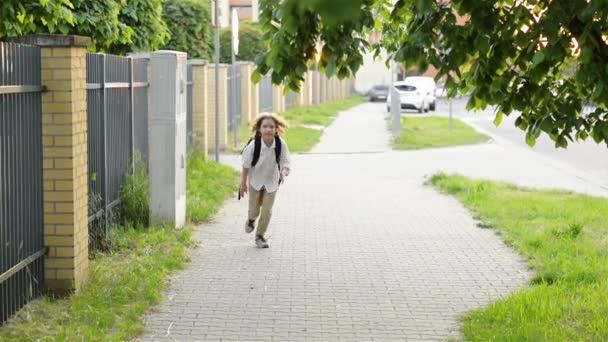 Colegial sonriente con la bolsa de la escuela corriendo en día soleado. Chico yendo a casa desde la escuela . — Vídeos de Stock