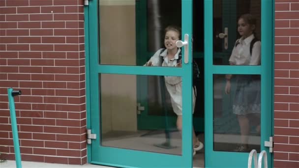 Niños sonrientes de la escuela primaria felices de ir a casa. Alegre escuela niñas y niños usando mochila y corriendo fuera de la escuela en las lecciones . — Vídeo de stock