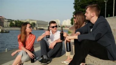 Dört Genç Arkadaş Bir Şirket Nehir tarafından bir Chill having, Onlar Sohbet, Gülüyor, Bira Içiyor. Casual Wear, Summertime, Parlak Işık Gün Batımı. Mutlu, Genç ve Özgür Olmak.