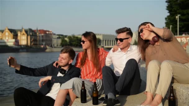 Studentengruppe beim Selfie über dem Universitätsgebäude. vier junge glückliche Studenten machen Selfie und lächeln im Freien. Freunde haben viel Spaß, verbringen Zeit miteinander und trinken Bier. — Stockvideo