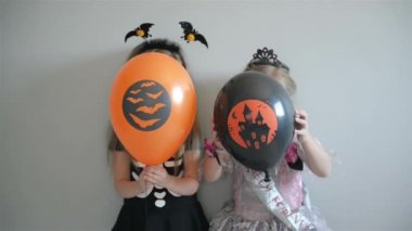 Gülümseyen kız mutlu Cadılar Bayramı kostümleri giymiş hava balonları tutarak ve poz.
