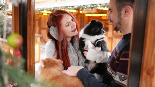 연인 커플 귀 염 둥이 강아지와 함께 껴 안고 있다. 그들은 함께 좋은 분위기가 있다. 옷된 구 뒤에 크리스마스 불빛. — 비디오