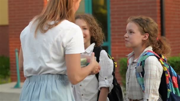 Onderwijs, familie en zorg concept. Liefdevolle moeder geeft haar kinderen school lunch in de buurt van de school. — Stockvideo