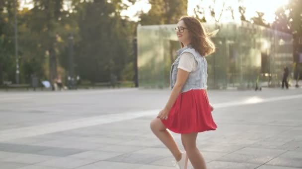 Lycklig kvinna lyssnar på musik och dansar med hörlurar utomhus. Flicka i casual kläder med lockigt frisyr i Urban bakgrund. — Stockvideo