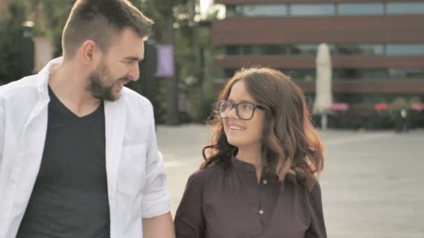 Feliz por estarmos juntos. Visão traseira do belo casal jovem de mãos dadas e olhando um para o outro com sorriso enquanto caminhava pela rua da cidade — Vídeo de Stock