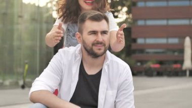 Genç bir kız bir adamın gözlerini kapatır ve güler. İlişki, dostluk ve aşk teması.