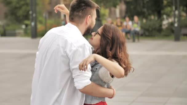 Casal jovem afetuoso abraçando e compartilhando um beijo romântico enquanto estão juntos em uma rua na cidade — Vídeo de Stock