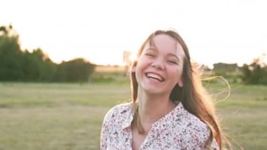 Kıvırcık saçlı güzel genç kadının geri görünümü şehir caddesinde yürürken, sonra kameraya döner, neşeyle gülümseyen Anlar mutluluk neşeli ruh hali. Yavaş çekim, kadın portresi, güneş merceği