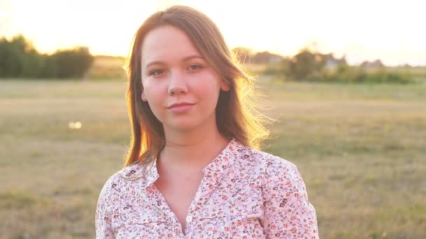 Vue arrière de la belle jeune femme aux cheveux bouclés marchant dans la rue de la ville, puis elle se tourne vers la caméra, souriant joyeusement Moments de bonheur humeur joyeuse. Mouvement lent, portrait féminin, lentille solaire — Video