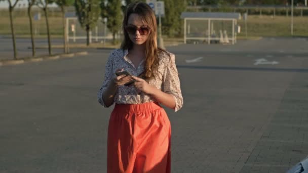 Beautiful caucasian girl walking down the street looking at her cell phone was almost hit by a car. Concept - smartphone addiction. — Stock Video