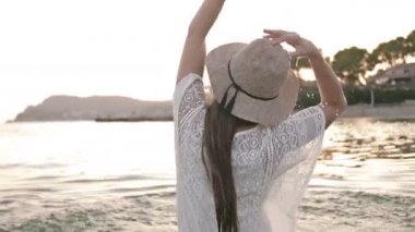 O okyanusta duruyor ve yan yana döner gibi elbise kız elleriyle turkuaz su sıçrayan. Yaz tatilinin tadını çıkaran kadın turist.