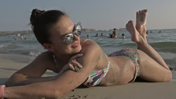 Женщина загорает на пляже, показывая ноги с телом на пляже бикини и красивой здоровой кожей. Женская модель в отпуске. Пляжные путешественники — стоковое видео