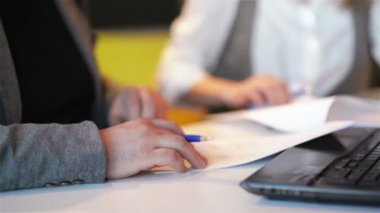 Ofiste birlikte çalışan birkaç Iş arkadaşları. İki Iş Işçisi dizüstü yeni proje hazırlanıyor. Onlar bir not defterinde ayrıntıları yazmak.