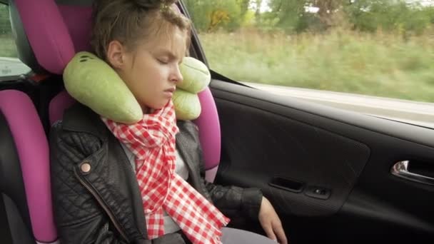 Viaje por carretera de la infancia y el concepto de la gente - niña adolescente durmiendo en el asiento del coche del bebé con almohada de viaje — Vídeo de stock