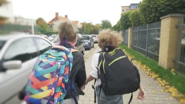 Crianças em idade escolar fogem da escola com mochilas. Infância feliz, Feiticeiras, hooligans . — Vídeo de Stock