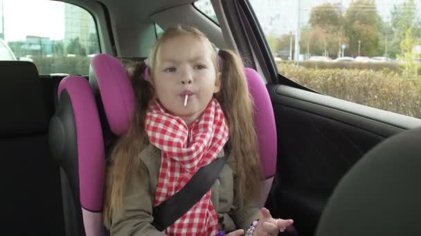 Child in the backseat of a car traveling on road, looking out window daydreaming — Stockvideo