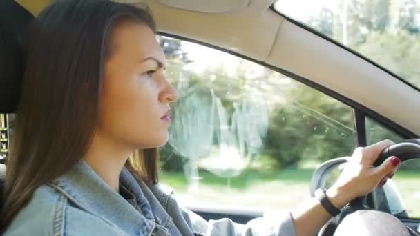 Portret van een prachtige jonge vrouw rijdende auto door grote Sunny City. Camera neergeschoten gemaakt van de passagier. — Stockvideo