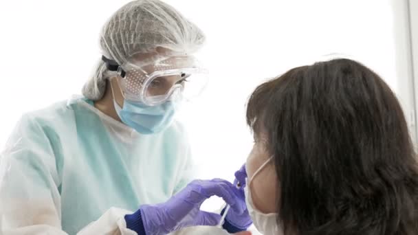 Sjuksköterska i skyddsdräkt injicerar vaccinet genom näsan på patienten. Nasal vaccination. — Stockvideo