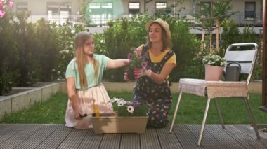 Anne ve genç kız saksı çiçeği ektiler. Pet onların yanında oynuyor. Takım çalışması kavramı, yakınlık, aileyle boş zaman geçirmek..