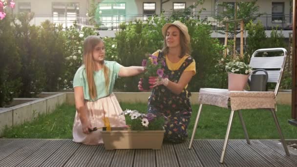 Mère et fille adolescente plantent des fleurs en pot. Pet joue à côté d'eux. Concept de travail d'équipe, proximité, temps libre en famille . — Video