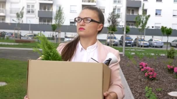 A lo largo de la calle hay una triste joven que acaba de perder su trabajo. En sus manos hay una caja con pertenencias personales. Crisis económica . — Vídeos de Stock