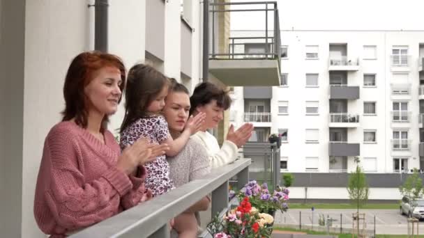 Quatro mulheres de diferentes idades, de pé na varanda de um edifício residencial, aplaudem alegremente. As pessoas se alegram com o fim da epidemia de coronavírus . — Vídeo de Stock