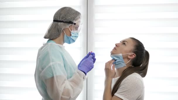 Nasal vaccination. Medicinsk personal i skyddsdräkt ger ett vaccin genom näsan till en ung patient. Övergångsbestämmelser. — Stockvideo