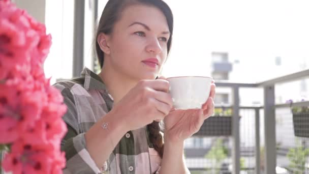 Aantrekkelijke vrouw drinkt koffie op haar balkon thuis. — Stockvideo