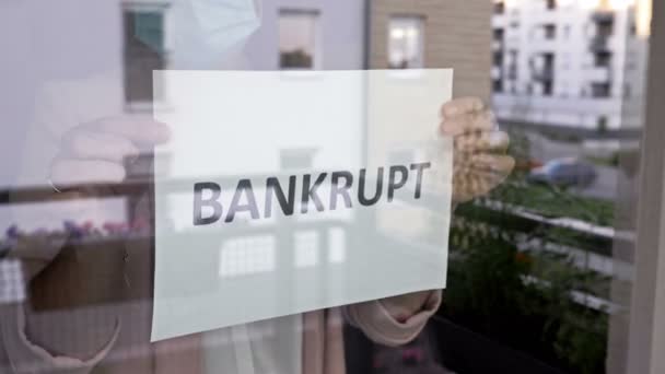 医療マスクの施設のオーナーは、窓にBANKRUPTサインを掛けます。中小企業に対するCOVID-19パンデミックの影響. — ストック動画