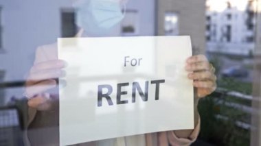Tıbbi maskeli kurumun sahibi pencereye bir RENT tabelası asıyor. Küçük işletme sahipleri COVID-19 salgınıyla başa çıkamıyor.