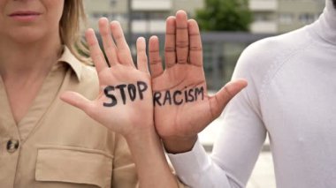 Beyaz bir kız ve siyah bir adamın avuçlarında RACISM yazısını durdurun. Irkçılığı durdur.