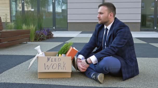 메디컬 마스크를 입은 슬픈 중년의 관리자가 직장을 잃은 후 자신의 개인 소지품과 함께 앉아 있습니다. COVID-19 대유행으로 인한 실직. — 비디오