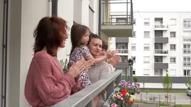 Fyra kvinnor i olika åldrar, stående på balkongen i ett bostadshus, glatt applådera. Folk gläds i slutet av coronavirusepidemin. — Stockvideo