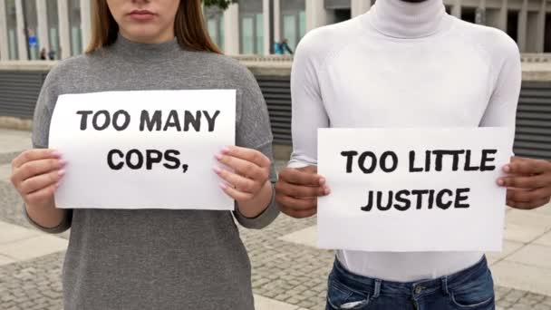 Burschen und Mädchen verschiedener Nationalitäten protestieren gegen Rassenungleichheit. Sie halten Plakate in den Händen, auf denen viele Polizisten und kleine Richter zu sehen sind.. — Stockvideo