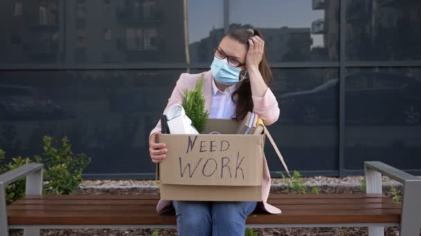 Jonge vrouw verloor haar baan door de economische crisis tijdens de COVID-19 pandemie. Op de doos van haar persoonlijke spullen staat geschreven NEED WORK. — Stockvideo