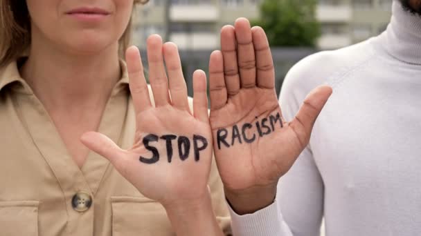 Стоп RACISM написано на ладонях белой девушки и черного парня. Концепция "Остановить расизм" . — стоковое видео