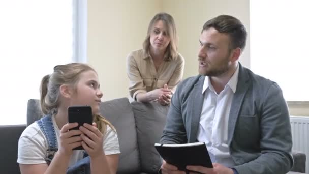 Probleme der Elternschaft in der Familie. Eltern schimpfen sehr auf eine Teenagertochter für etwas. Das Mädchen blickt gleichgültig auf den Telefonbildschirm und verärgert ihre Eltern noch mehr. — Stockvideo