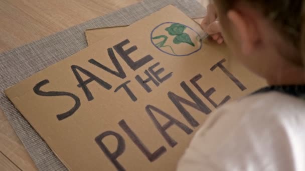 Schoolmeisje maakt een poster SAVE THE PLANET. — Stockvideo