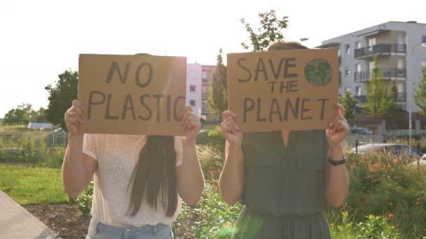 Twee jonge vrouwen staan met de posters SAVE THE PLANET en NO PLASTIC. Zij leveren een haalbare bijdrage aan de bestrijding van de wereldwijde vervuiling van de natuur. — Stockvideo